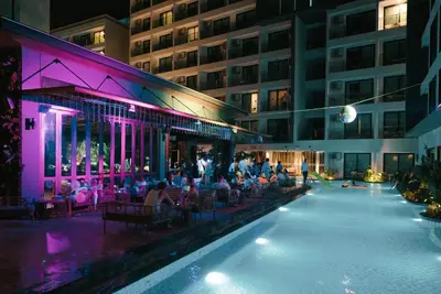 a group of people sitting around a swimming pool at night at Wekata Luxury in Kata Beach