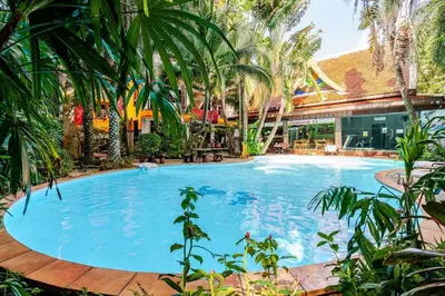 a large swimming pool in a resort with palm trees at Naiharn Pearl Condo Hotel by VillaCarte in Nai Harn Beach