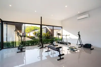 a gym with cardio equipment in a room with large windows at Thames Tara Private Pool Villa Rawai Phuket in Rawai Beach