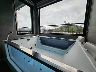 a bath tub in a room with two windows at Little Loft Hotel in Phuket Town