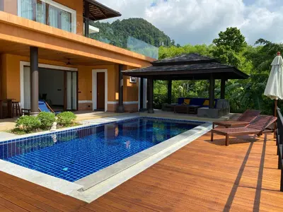 a pool with an umbrella next to a house at Villa Tango Victoria Resort, Koh Yao Noi in Ko Yao Noi