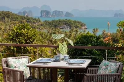a table and chairs with a view of the water at SAMSAM Yao Noi - ANDAMAN MAGIC & ART VILLAS in Ko Yao Noi