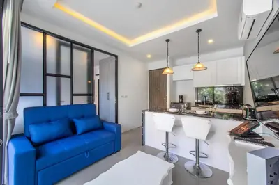 a living room with a blue couch and a kitchen at 1BDR Apartment near Surin beach #210 in Surin Beach