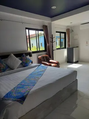 a bedroom with a large bed and a chair at Marin' s Home in Thalang