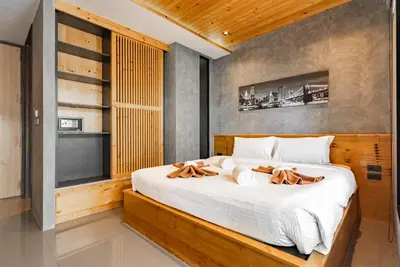 a bedroom with a large bed with two wooden logs at Relife The Windy by VillaCarte in Rawai Beach