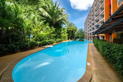 a large blue swimming pool next to a building at Mai Khao Beach Condo by VillaCarte in Mai Khao Beach