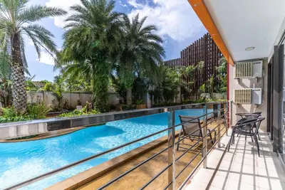 a swimming pool with chairs and palm trees on a balcony at Mai Khao Beach Condo by VillaCarte in Mai Khao Beach