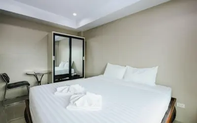 a bedroom with a white bed with towels on it at Tyler Cherngtalay in Ban Pak Lak
