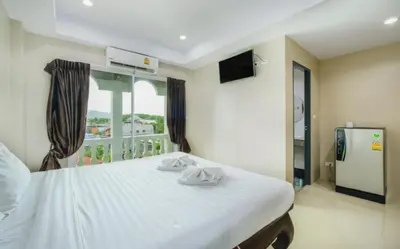 a bedroom with a large white bed with a window at Tyler Cherngtalay in Ban Pak Lak