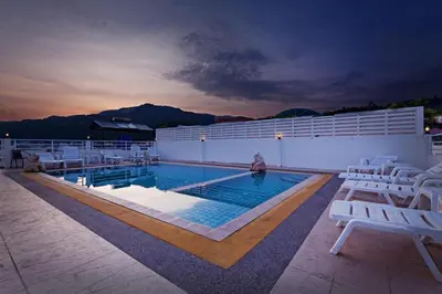 a swimming pool with white lounge chairs next to a building at Garden Phuket Hotel in Patong Beach