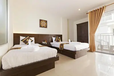 a bedroom with two beds and a balcony at Garden Phuket Hotel in Patong Beach