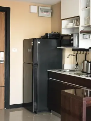 a kitchen with a black refrigerator in a room at APARTMENTS MBC in Mai Khao Beach