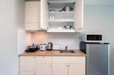 a kitchen with white cabinets and a sink and a microwave at Luxury Apartment at Title Residencies Naiyang Beach in Phuket Town