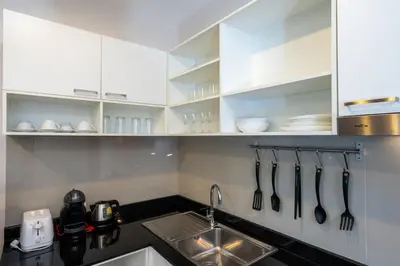 a kitchen with white cabinets and a sink with utensils at The Title Rawai Beach West Wing in Phuket Town