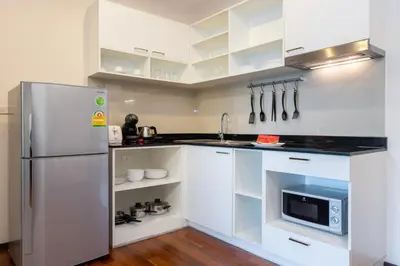 a kitchen with white cabinets and a stainless steel refrigerator at The Title Rawai Beach West Wing in Phuket Town