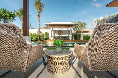 two wicker chairs and a table on a patio at Botanica Bangtao Beach Villa in Phuket Town