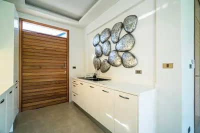 a kitchen with white cabinets and a wooden door at Cocoon Villa - Peaceful private pool villa in north Phuket in Phuket Town