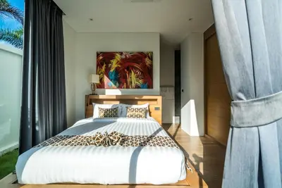 a bedroom with a large bed and a painting on the wall at Cocoon Villa - Peaceful private pool villa in north Phuket in Phuket Town