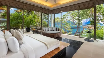 a bedroom with a large bed and large windows at Villa Chelay in Kamala Beach