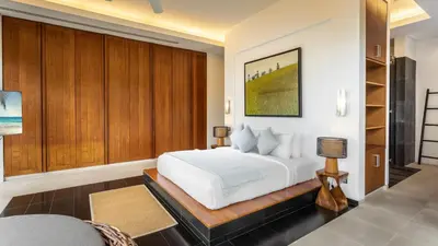 a bedroom with a white bed and wooden cabinets at Villa Chelay in Kamala Beach