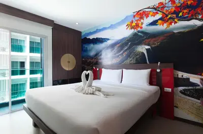 a bedroom with a large bed with a painting on the wall at The AIM Patong Hotel in Patong Beach