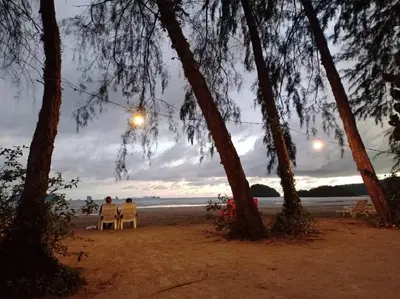 two people sitting in chairs on the beach at sunset at Sand Beach Bungalow in Klong Muang Beach