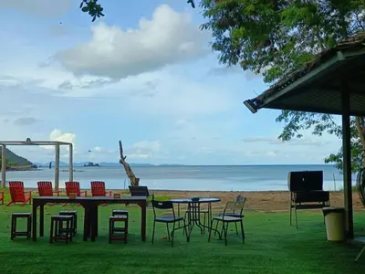 a table and chairs on the grass near the beach at Charcoal Panwa Beach Phuket in Ban Tha Khreng