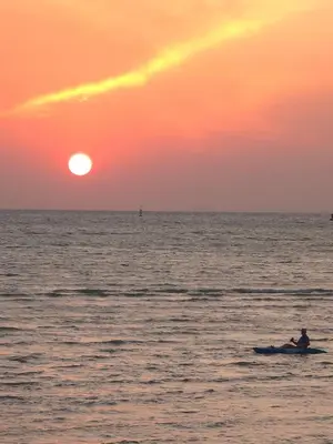 a person in a canoe in the ocean at sunset at Charcoal Panwa Beach Phuket in Ban Tha Khreng