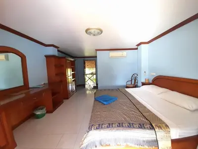 a bedroom with a large bed and a mirror at Lam Sai village hotel Koh Yao Noi in Ko Yao Noi