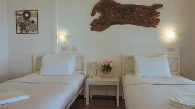 two beds in a room with white sheets and flowers at Holiday Resort - SHA Plus in Ko Yao Noi