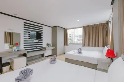 a hotel room with two beds and a television at Royal Beach Residence, Patong Beach in Patong Beach