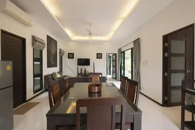 a dining room and living room with a table and chairs at Cocktail Palm Villa in Rawai Beach