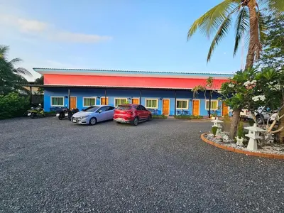 two cars parked in a parking lot in front of a building at นิวเวฟภูเก็ต in Ban Na Kok