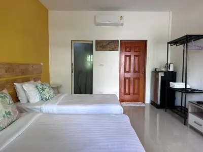 a bedroom with two beds and a red door at นิวเวฟภูเก็ต in Ban Na Kok