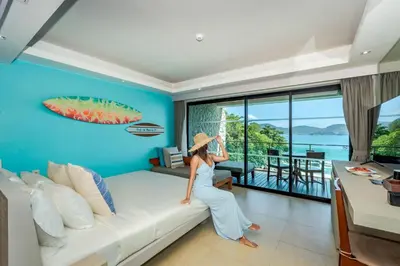 a woman is standing on a couch in a living room at Zenmaya Oceanfront Phuket, Trademark Collection by Wyndham in Patong Beach