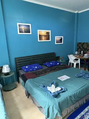a bedroom with a bed and a blue wall at San Antonio Beach Guesthouse & Restaurant in Kata Beach