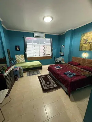 a bedroom with a large bed and a window at San Antonio Beach Guesthouse & Restaurant in Kata Beach