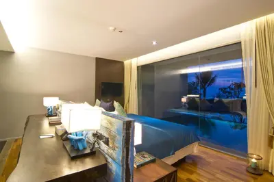a bedroom with a bed and a table and a window at Le Coral Resort in Natai Beach