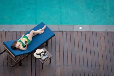 a woman laying on a chair next to a pool at Le Coral Resort in Natai Beach