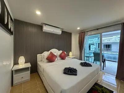 a bedroom with a bed with red pillows and a balcony at Inn Dulgence in Patong Beach