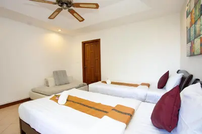 a bedroom with three beds and a ceiling fan at Heavenly Villas in Patong Beach