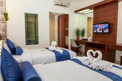 a hotel room with three beds and a television at Tuana Hotels Brook Pool Access in Chalong