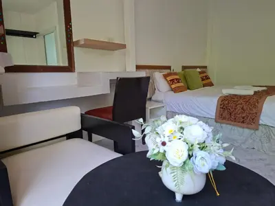 a room with two beds and a table with a vase of flowers at Suwita House in Nai Yang Beach