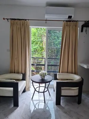 a living room with two chairs and a table and a window at Suwita House in Nai Yang Beach