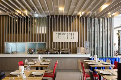 a restaurant with wooden tables and chairs and a kitchen at Mirage Express Patong Phuket Hotel in Patong Beach