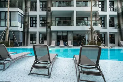 a swimming pool with chairs and a building at Apartment at Palmyrah Surin by Lofty in Surin Beach