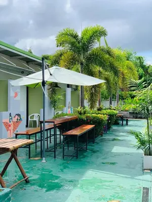 a patio with wooden tables and an umbrella at Rawai Whale Resort in Rawai Beach