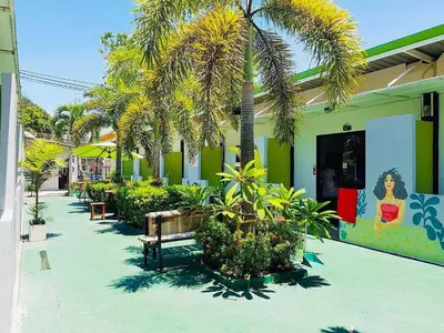 a courtyard with palm trees and a bench in front of a building at Rawai Whale Resort in Rawai Beach