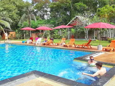 two people in a swimming pool with red umbrellas at Doo Dee Boutique Resort by Swiss Chalet in Ao Nang Beach