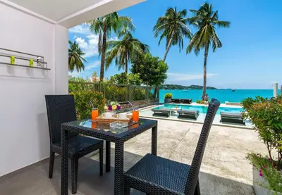 a table and chairs on a patio with a view of the ocean at Mango Tree Villa in Panwa Beach